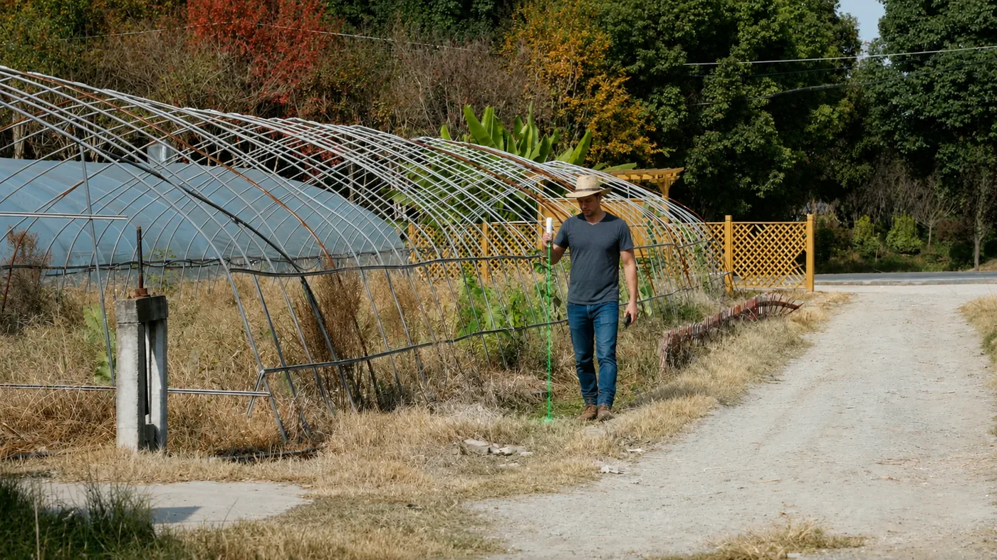 Farmer measuring a field boundary next to greenhouses